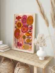 Stylised orange and yellow striped fish with abstract red and orange floral shapes on a pink, in an alternate framed mockup
