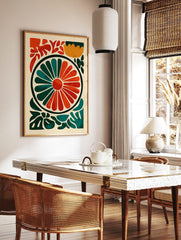 Abstract floral wheel art print with radiating orange and teal segments, surrounded by green, in a styled room mockup