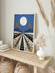Stylised landscape art print with large white moon, wheat plants, and geometric patterned, in an alternate framed mockup