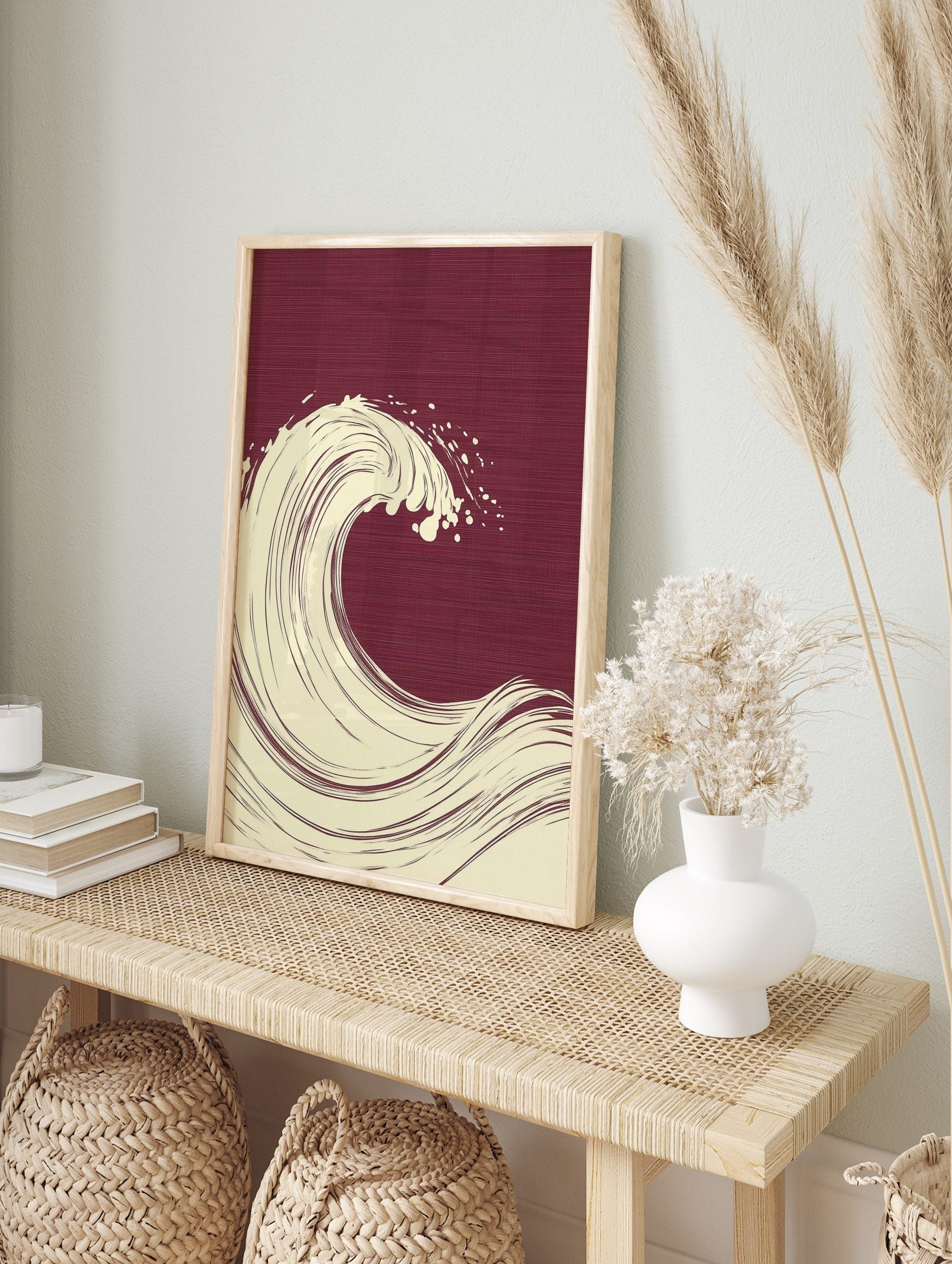 Stylised cream ocean wave illustration with spray on a deep burgundy textured background in, in an alternate framed mockup