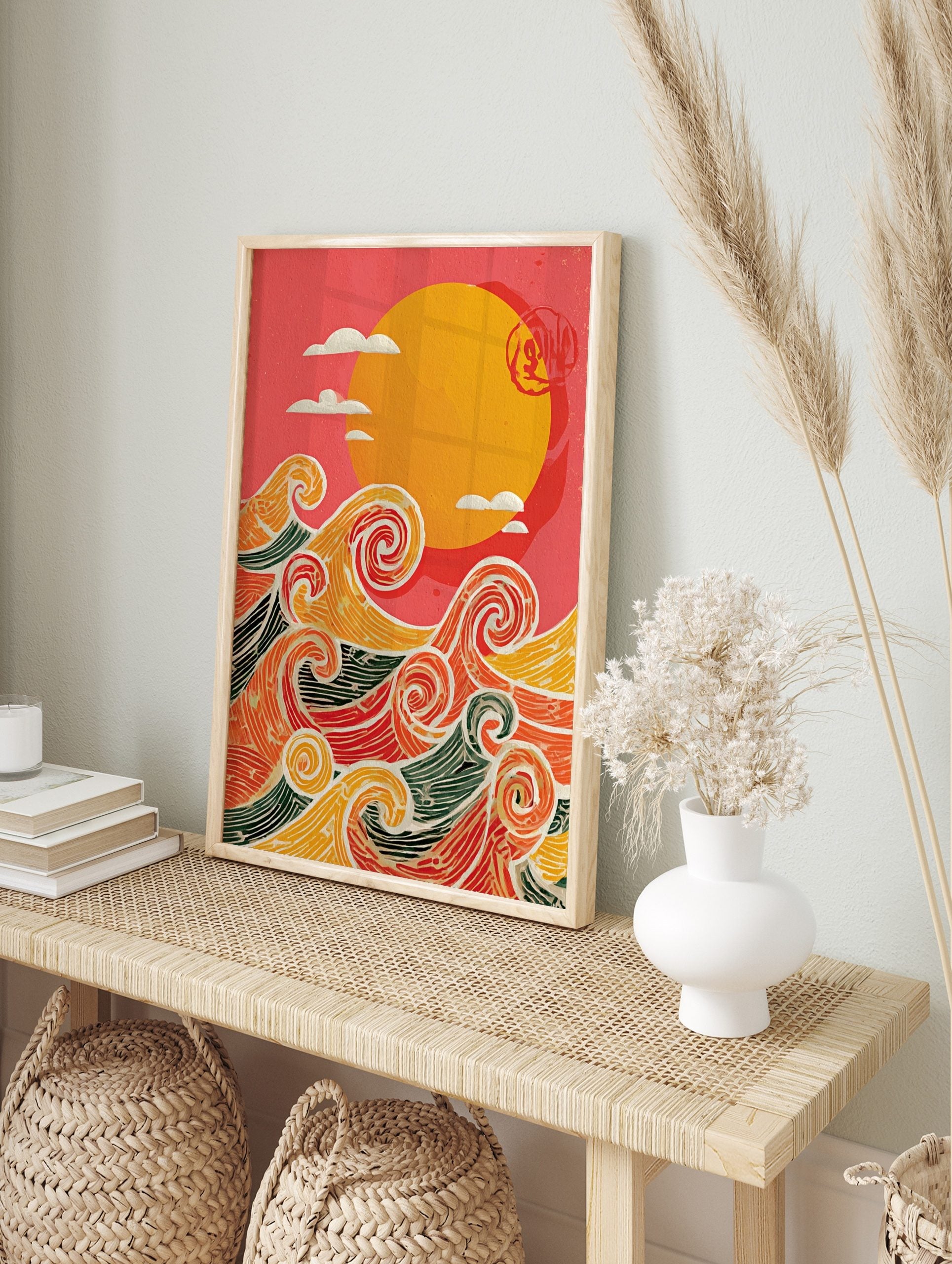 Stylised ocean waves in orange, red, yellow, green with white outlines, beneath a yellow sun, in an alternate framed mockup