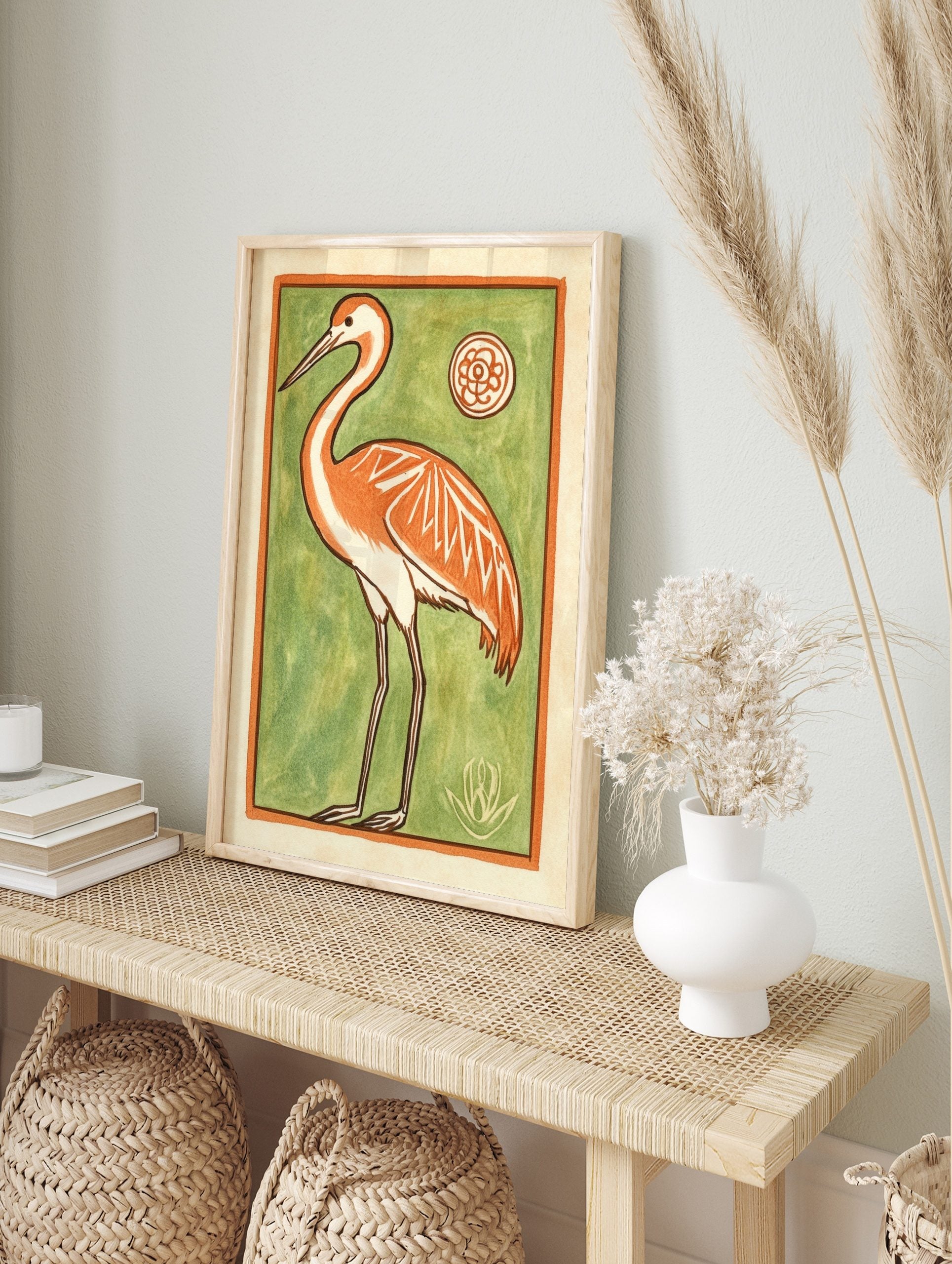 Stylised orange crane bird illustration with white accents on a vibrant green background, in an alternate framed mockup