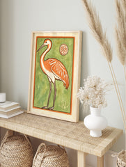 Stylised orange crane bird illustration with white accents on a vibrant green background, in an alternate framed mockup
