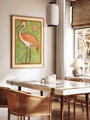 Stylised orange crane bird illustration with white accents on a vibrant green background, ornate, in a styled room mockup