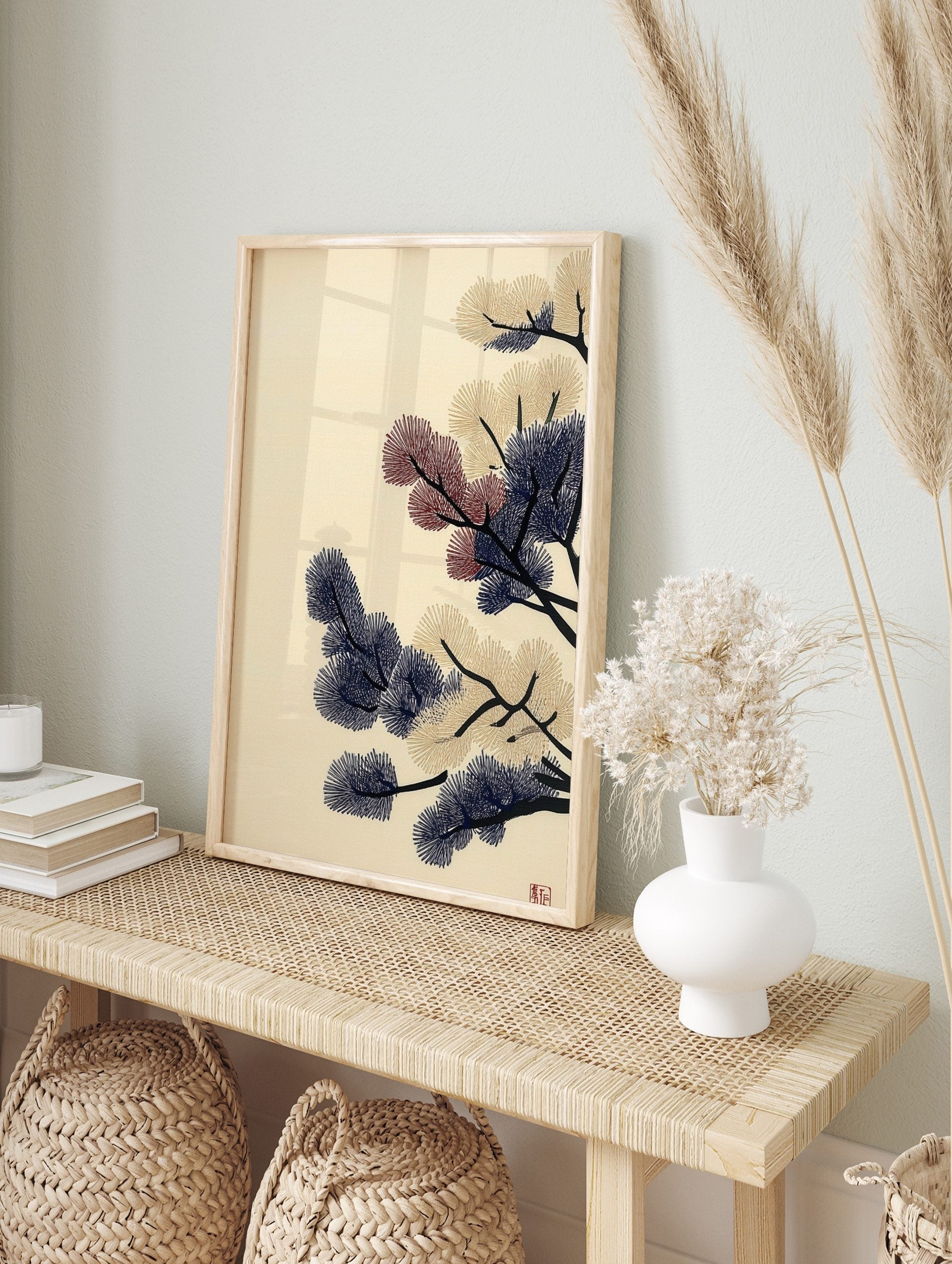 Stylised pine branches with navy blue, beige, and red needle clusters on a cream background, in an alternate framed mockup