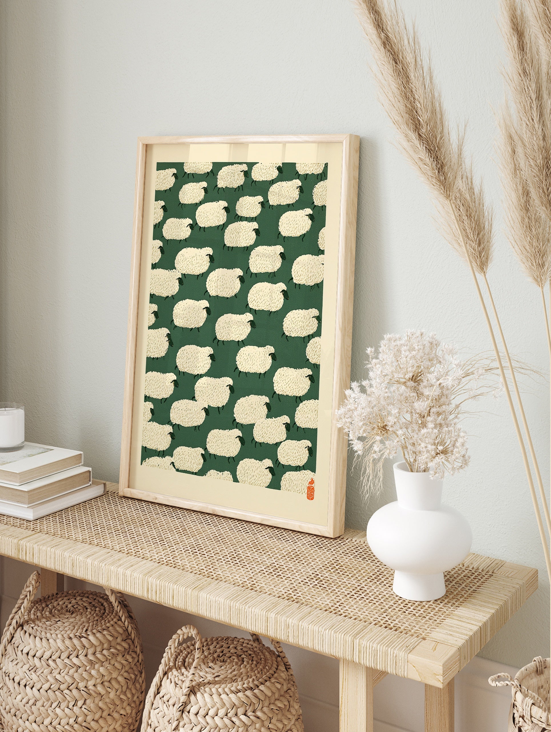 Repeating pattern of stylised cream sheep on a dark green background with a red seal in the, in an alternate framed mockup