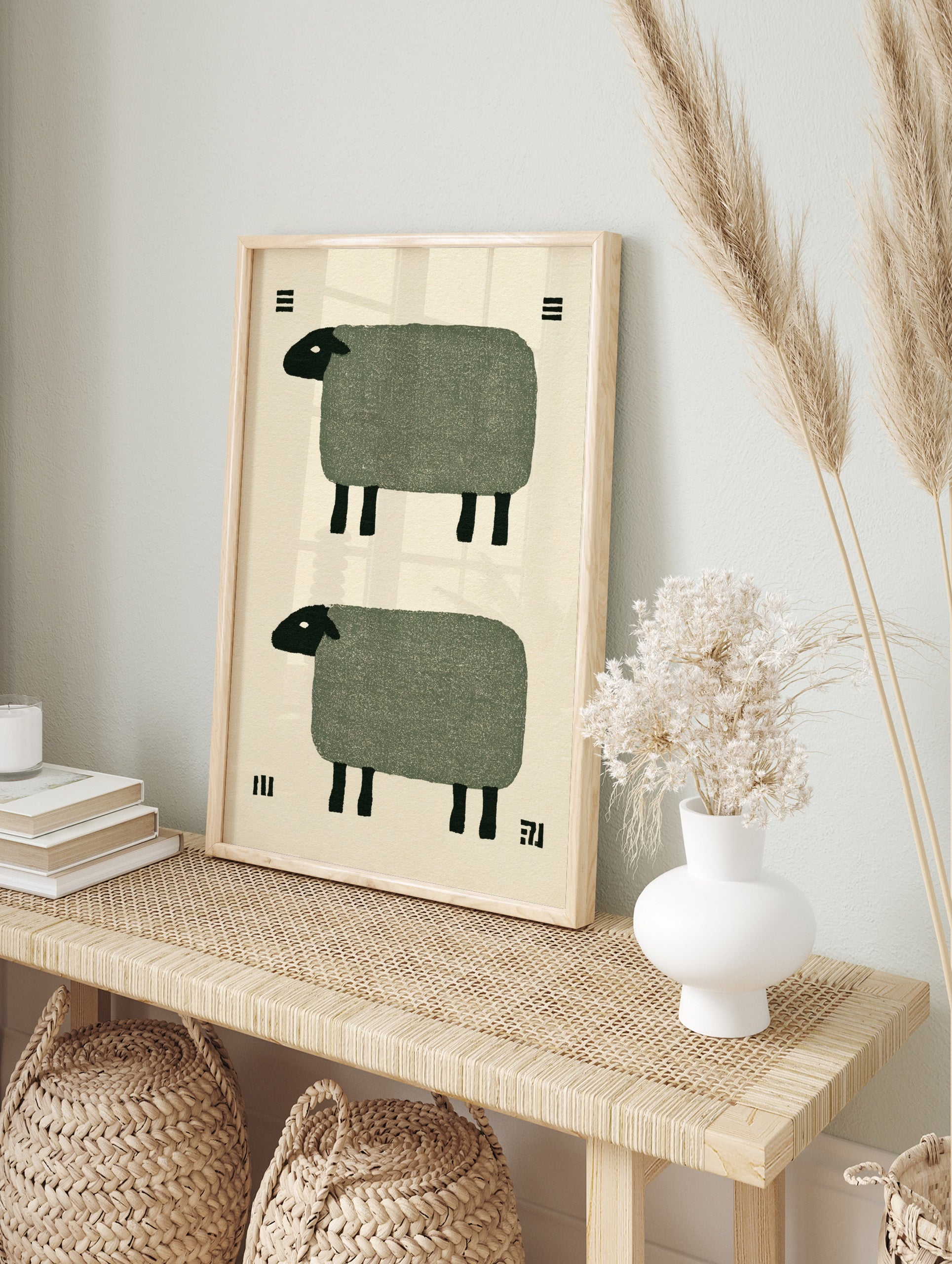 Minimalist art print of two stylized sheep with green bodies and black heads on a cream, in an alternate framed mockup