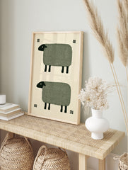 Minimalist art print of two stylized sheep with green bodies and black heads on a cream, in an alternate framed mockup