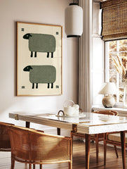 Minimalist art print of two stylized sheep with green bodies and black heads on a cream background, in a styled room mockup