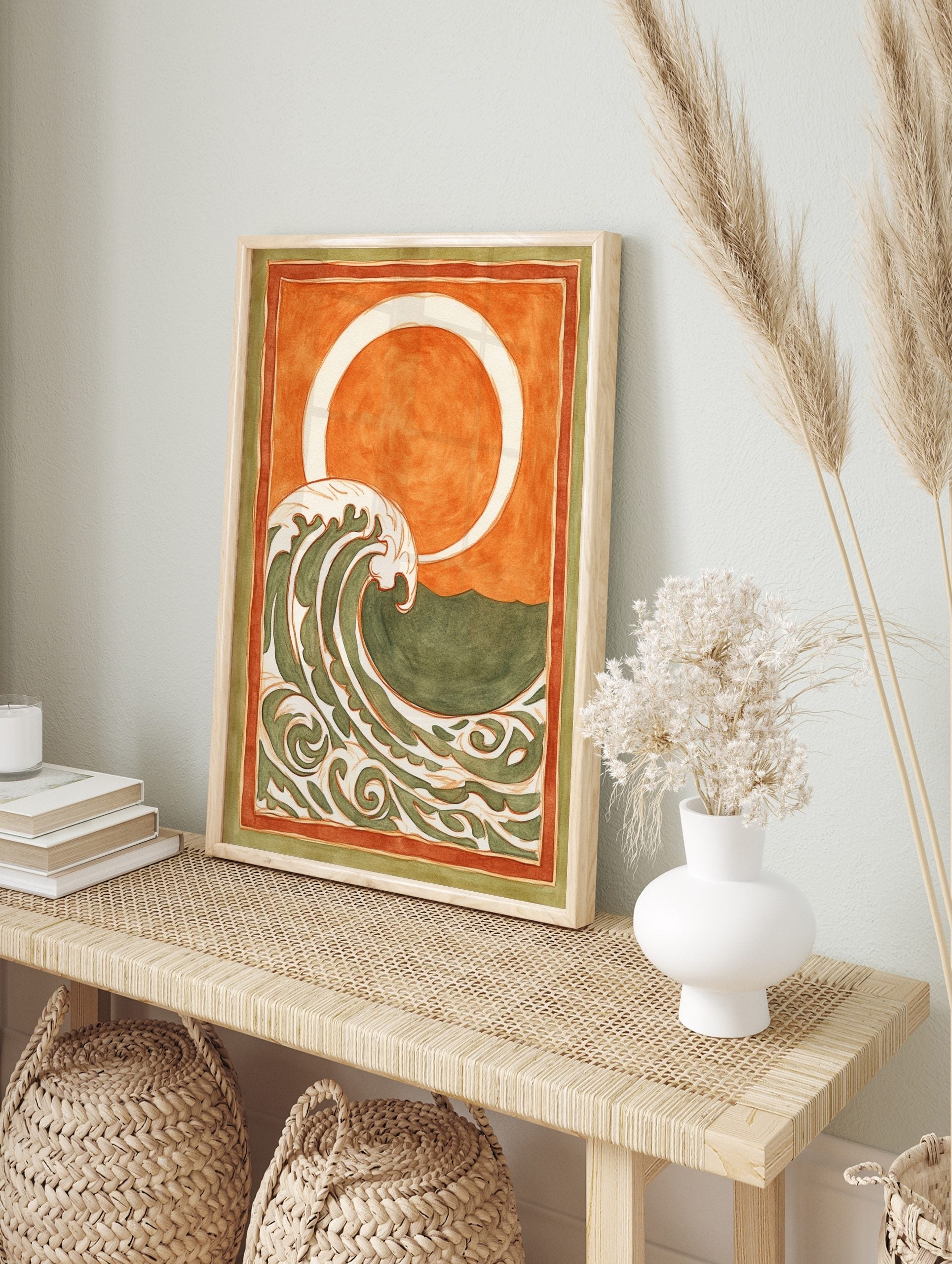 Stylised ocean wave art print with cream and green patterns, orange sky, white sun/moon, and, in an alternate framed mockup