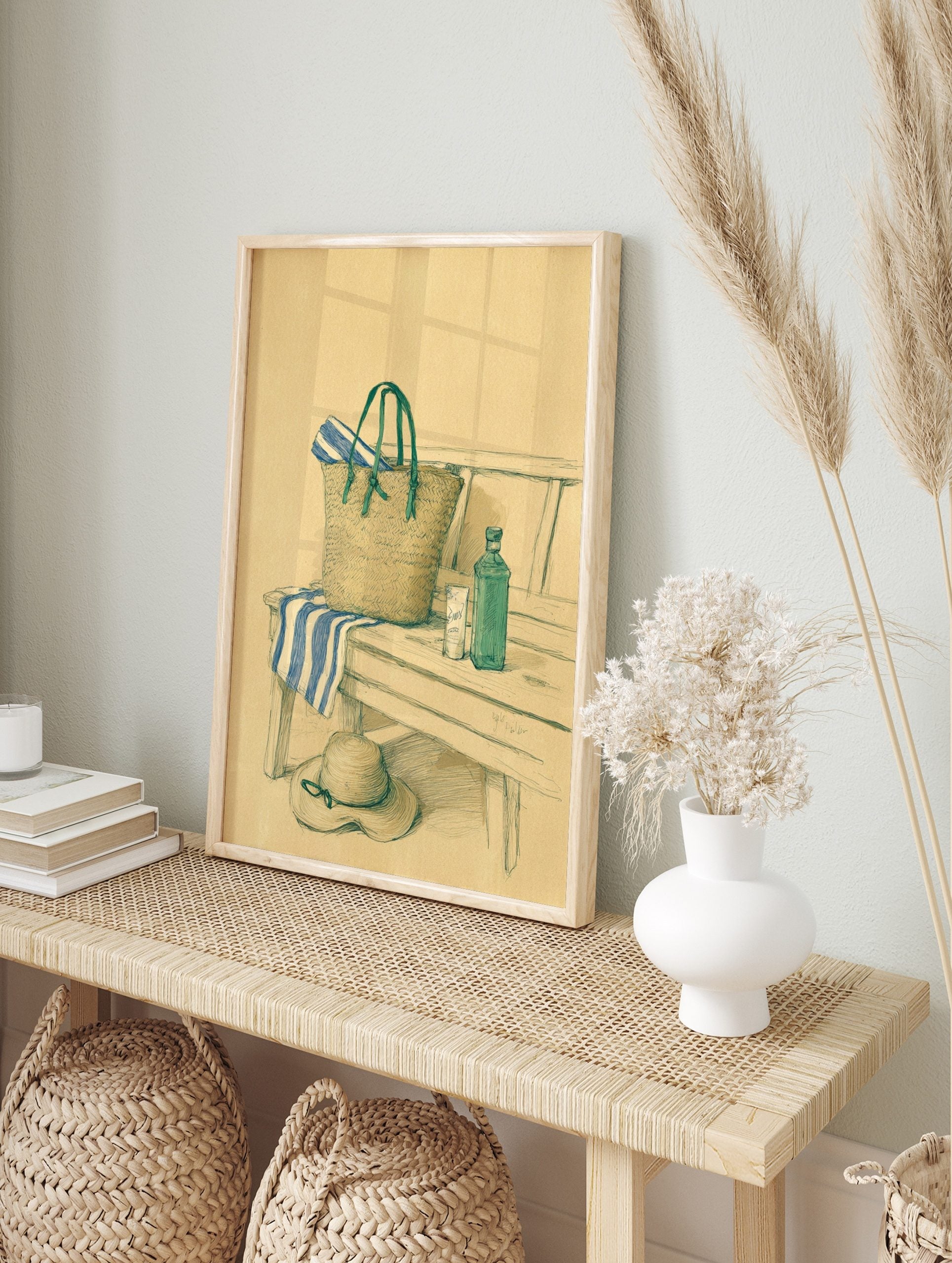 Illustrated still life of a straw beach bag, blue striped towel, and sun hat on a wooden bench, in an alternate framed mockup