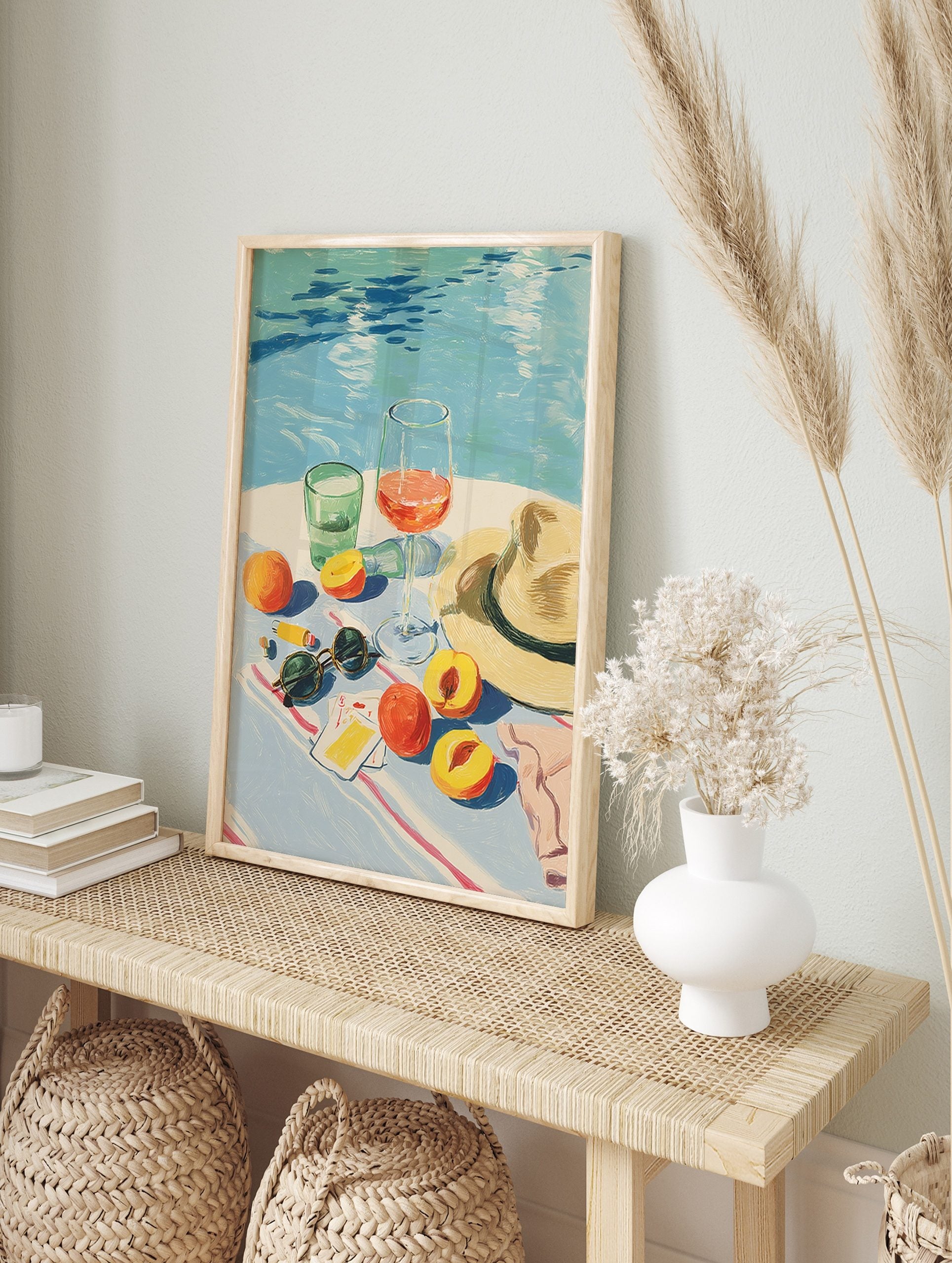 Illustrative summer still life with peaches, wine, water glass, sunglasses, and hat by a blue, in an alternate framed mockup