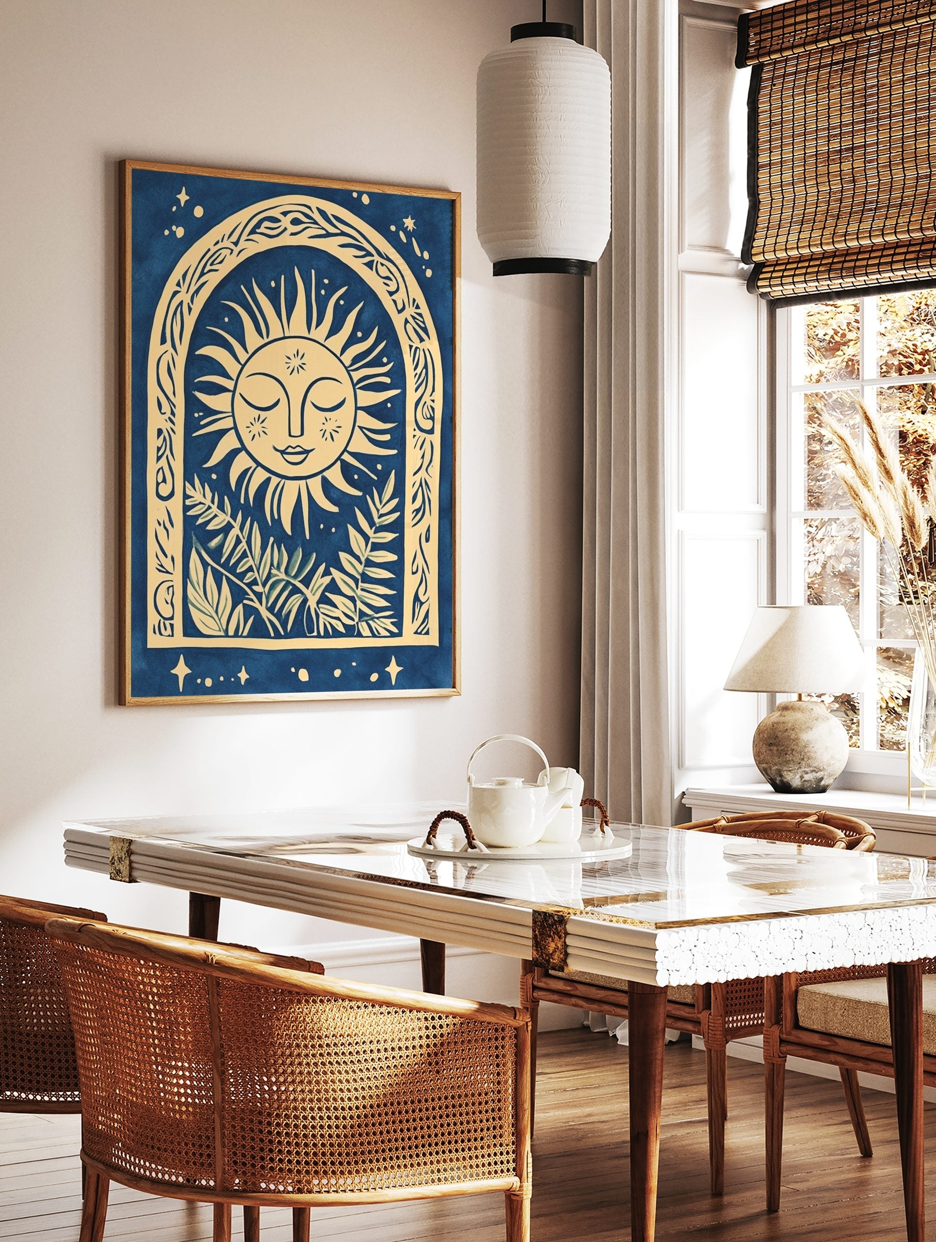 Illustrative sun face with closed eyes in an ornate arch with botanical leaves, blue and beige, in a styled room mockup
