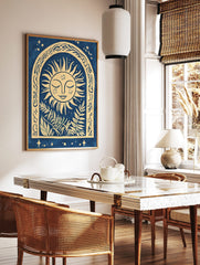 Illustrative sun face with closed eyes in an ornate arch with botanical leaves, blue and beige, in a styled room mockup