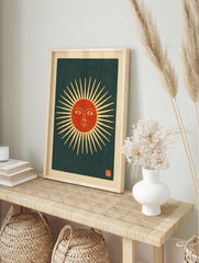Stylised sun face with radiating beams and a red centre on a dark background, in a vintage, in an alternate framed mockup