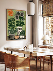Woodcut style print of sunflowers, cabbage, asparagus, pumpkin, and pitcher on a green background, in a styled room mockup