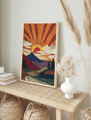Pointillist sunrise mountain landscape art print with orange sun rays, blue mountains, and a, in an alternate framed mockup
