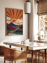 Pointillist sunrise mountain landscape art print with orange sun rays, blue mountains, and a river, in a styled room mockup