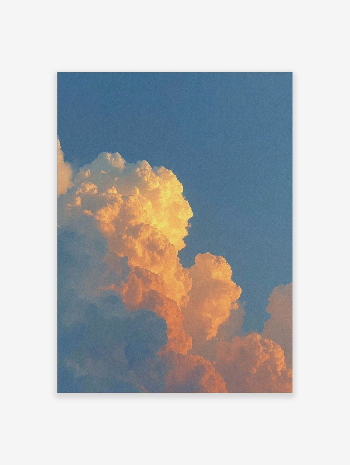 Dramatic orange and golden cumulus clouds against a clear blue sky during sunset