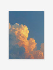 Dramatic orange and golden cumulus clouds against a clear blue sky during sunset