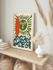 Illustrative wall art with red surfboard, green sun with face, and swirling blue ocean waves, in an alternate framed mockup