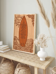 Illustrative art print of a decorative surfboard, smiling sun, and swirling waves in orange, in an alternate framed mockup