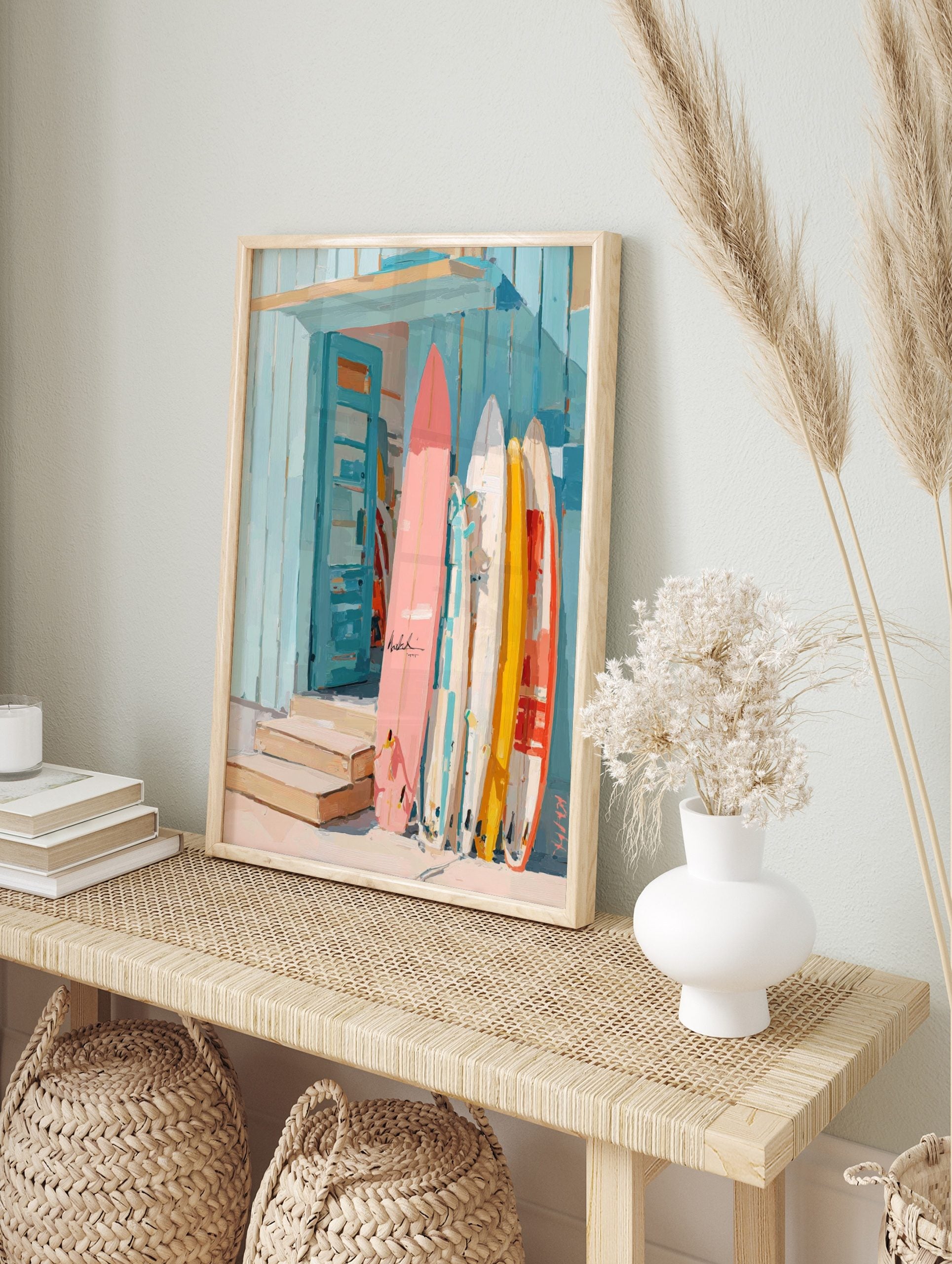 Colourful surfboards in pink, yellow, and white leaning against a blue wooden beach shack, in an alternate framed mockup