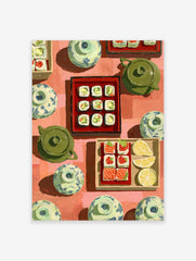 Overhead view of illustrative sushi rolls, salmon sashimi, lemon, green teapots, and patterned bowls on red background