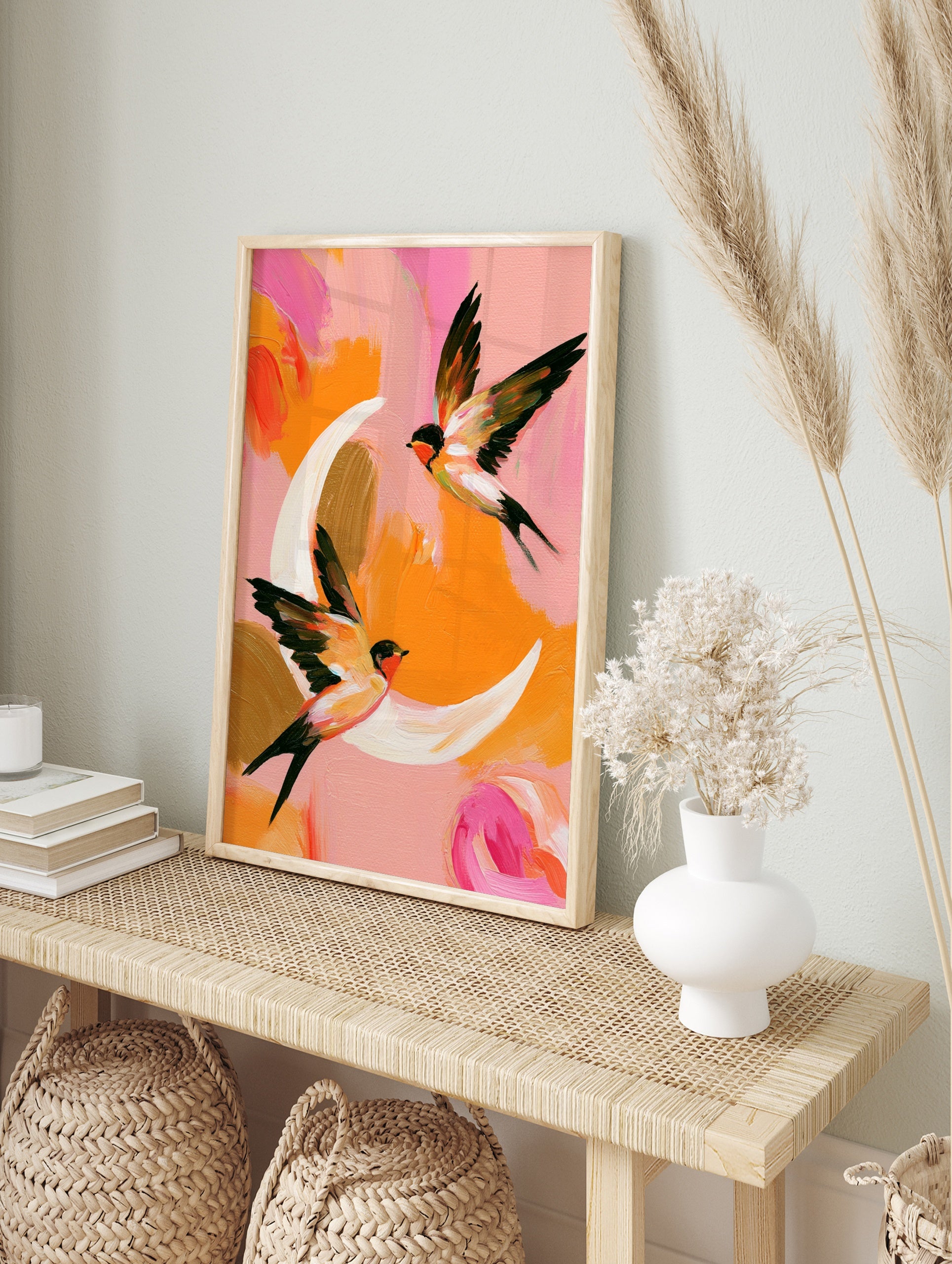 Two swallows in flight against a painterly pink and orange background, abstract bird wall art, in an alternate framed mockup