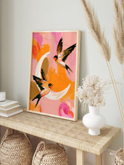 Two swallows in flight against a painterly pink and orange background, abstract bird wall art, in an alternate framed mockup