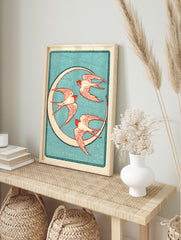 Vintage style illustration of three red swallow birds flying in a circle against a textured, in an alternate framed mockup