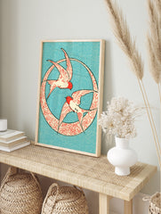 Two swallows in red and cream flying inside a circular patterned frame on a blue background, in an alternate framed mockup