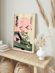 Illustrative print of swallows flying over traditional Japanese houses with tiled roofs and, in an alternate framed mockup