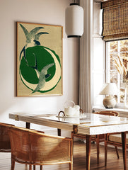 Stylised illustration of two swallows in flight with a green crescent moon on a textured tan, in a styled room mockup