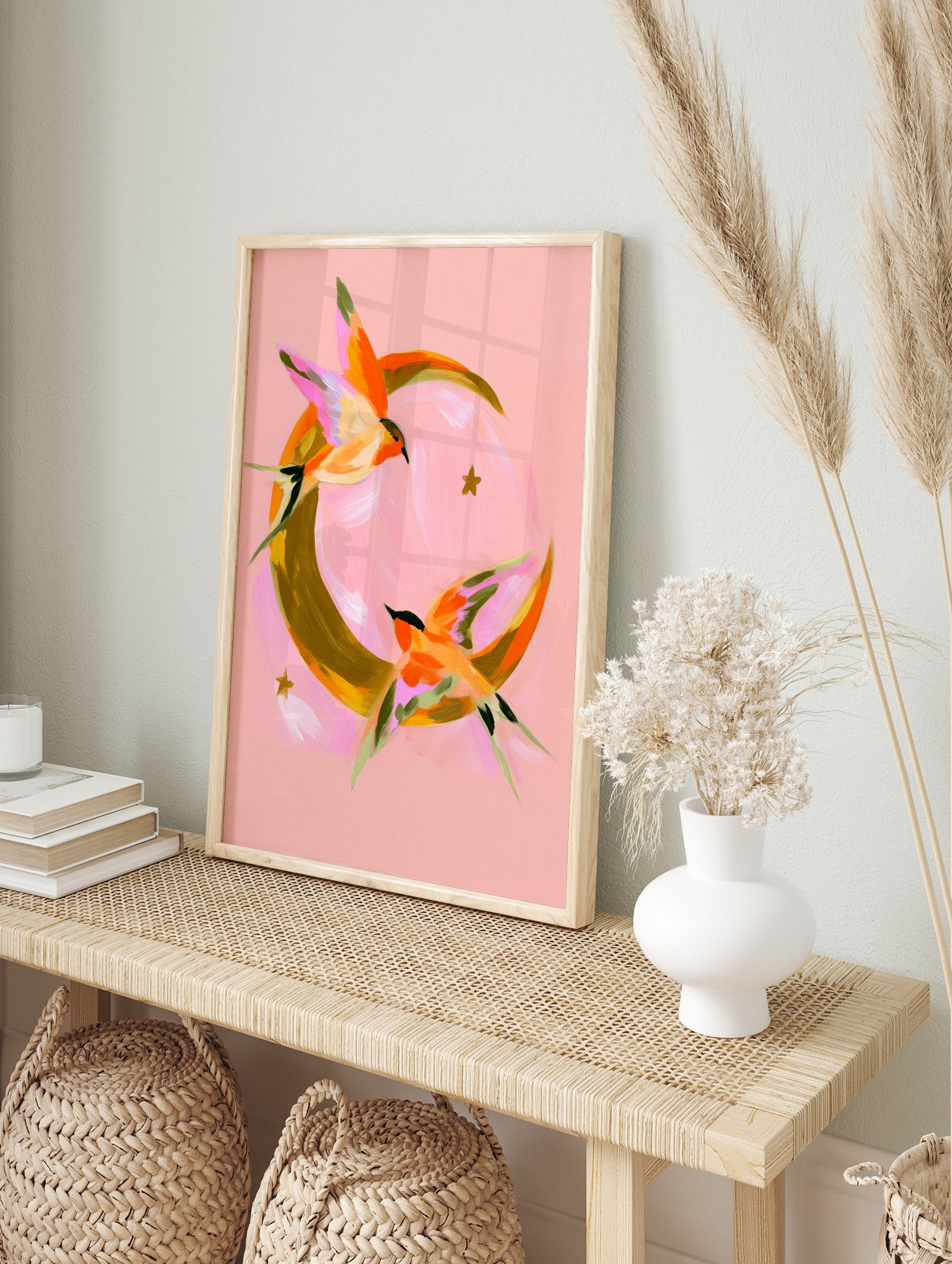 Abstract swallow bird illustration flying around a golden crescent moon on a pink background, in an alternate framed mockup