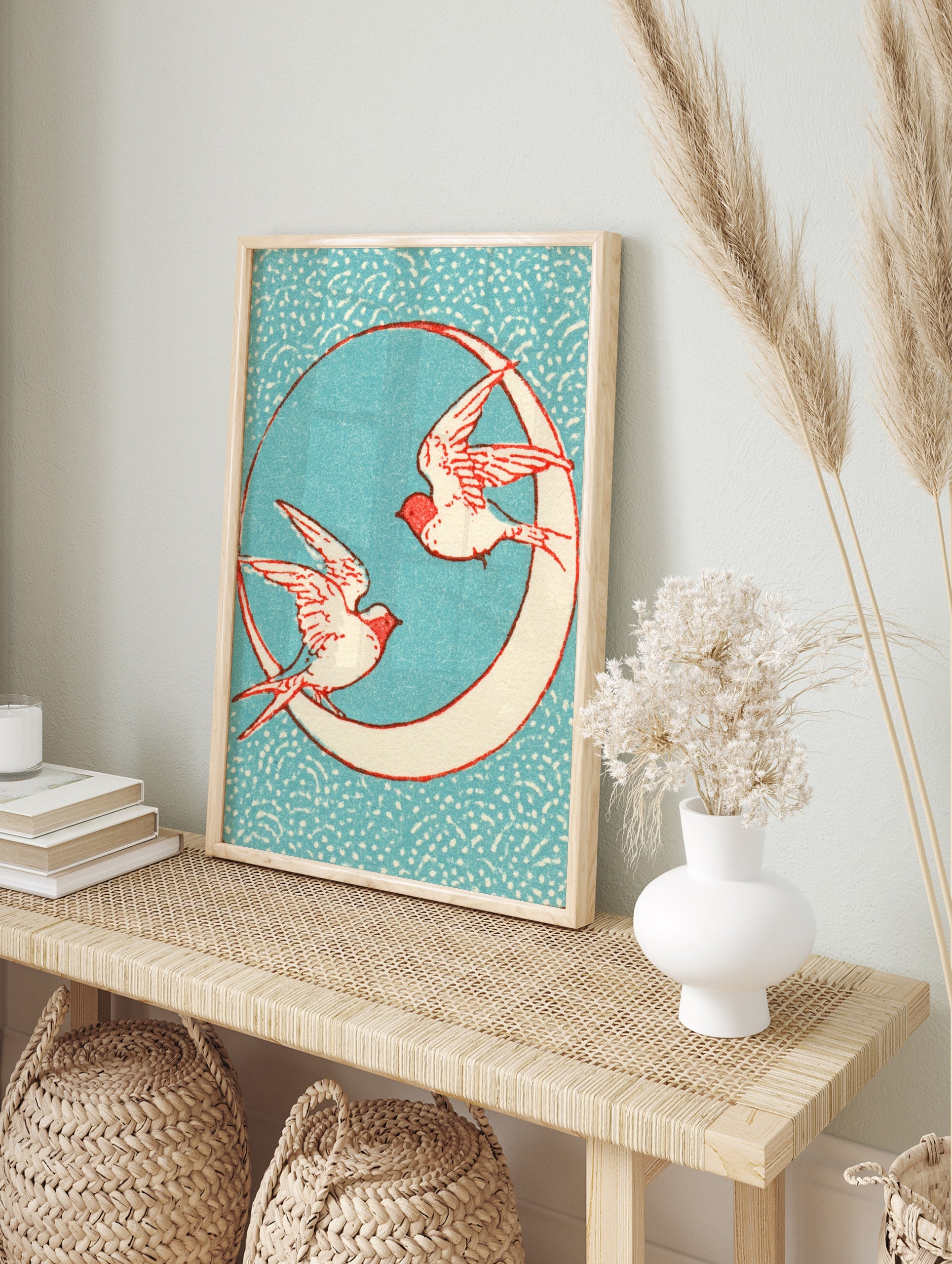 Vintage-style illustrative print of two swallows flying around a crescent moon against a, in an alternate framed mockup