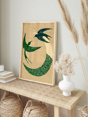 Circular art print of two green swallows in flight with a wave motif on a textured beige, in an alternate framed mockup