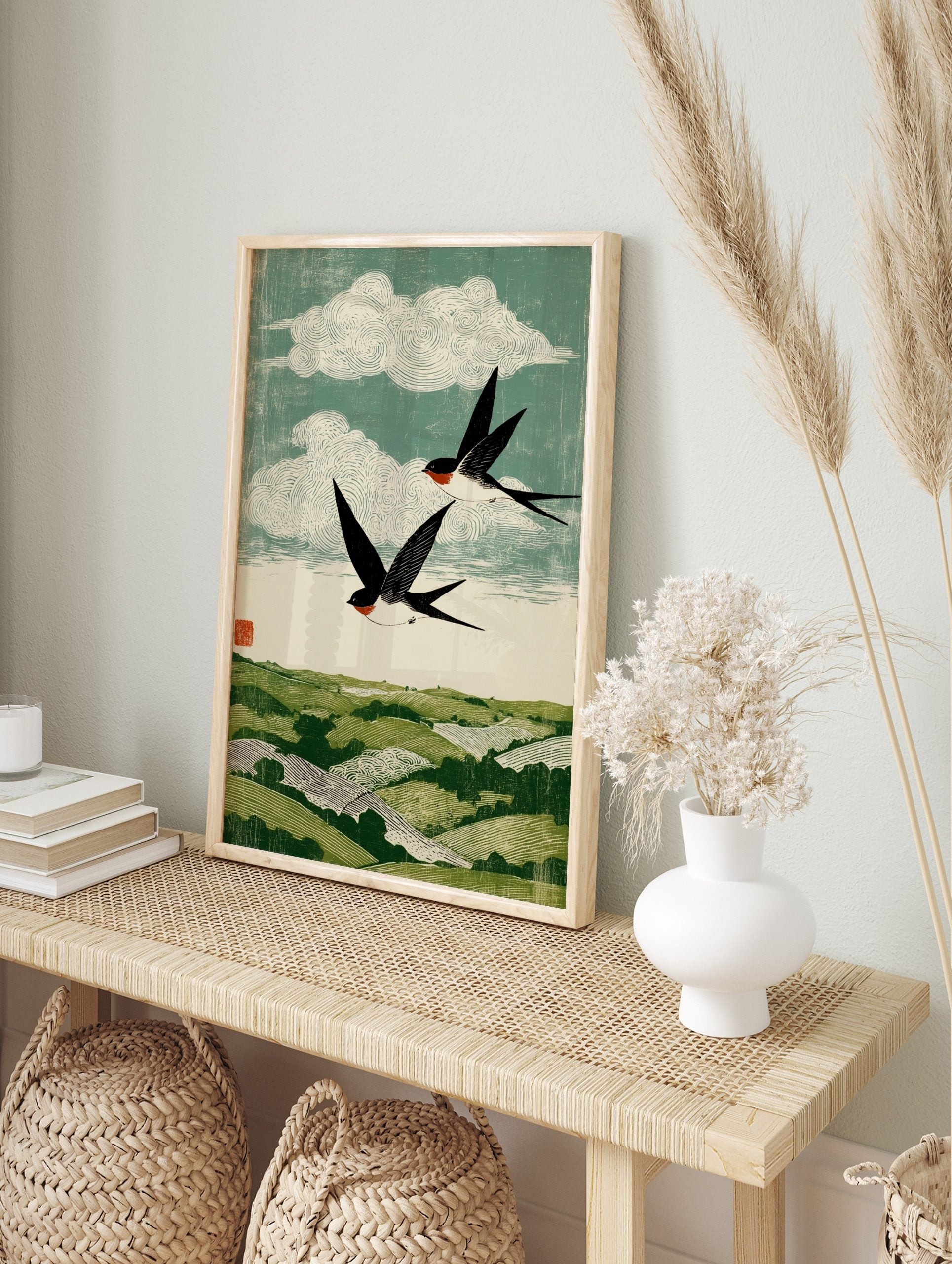 Woodblock style print of two black and white swallows with red throats flying over green, in an alternate framed mockup