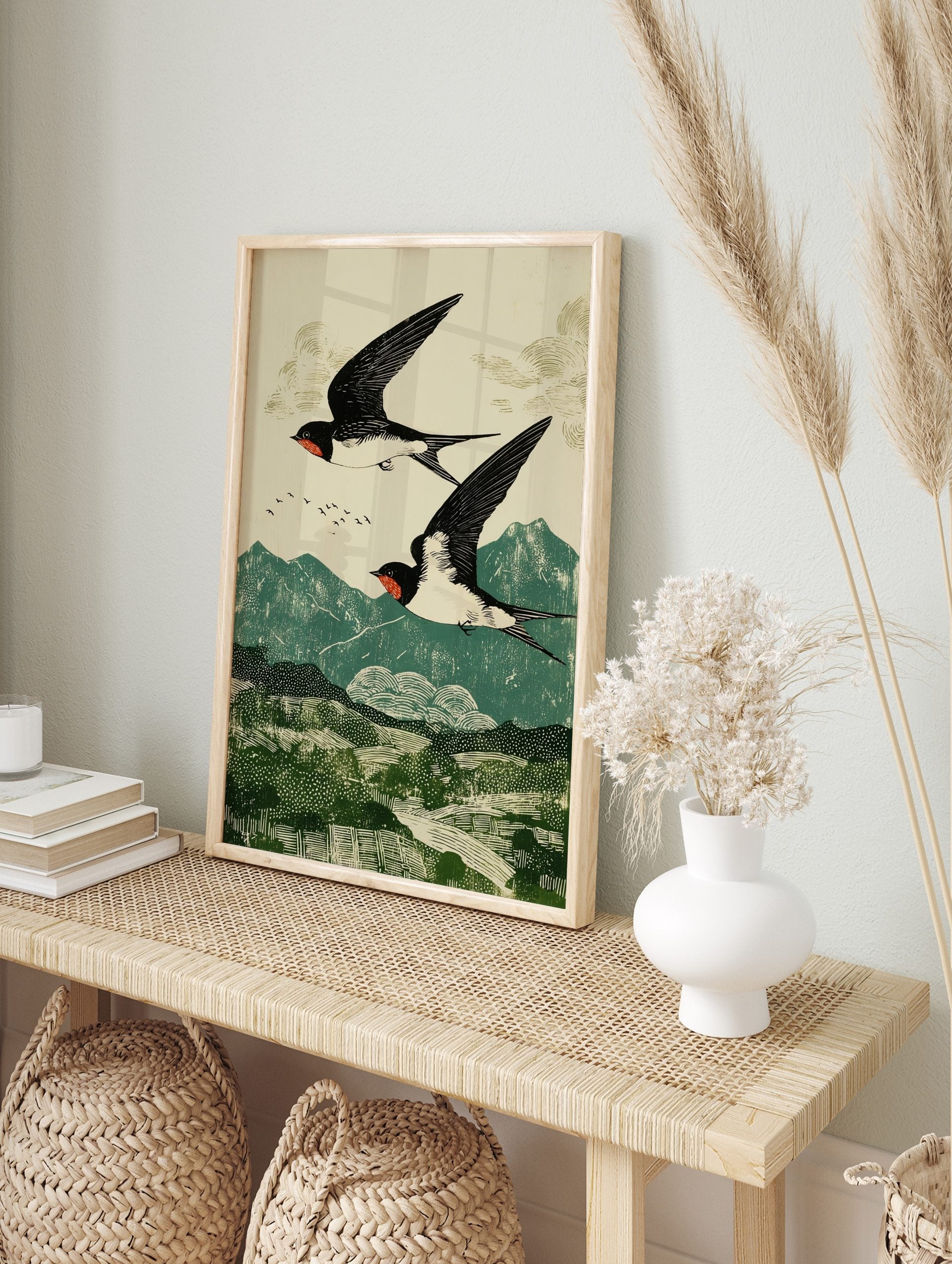 Two black and white swallows with red markings flying over green mountains in a woodblock, in an alternate framed mockup