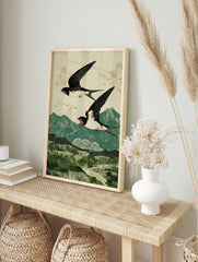 Two black and white swallows with red markings flying over green mountains in a woodblock, in an alternate framed mockup
