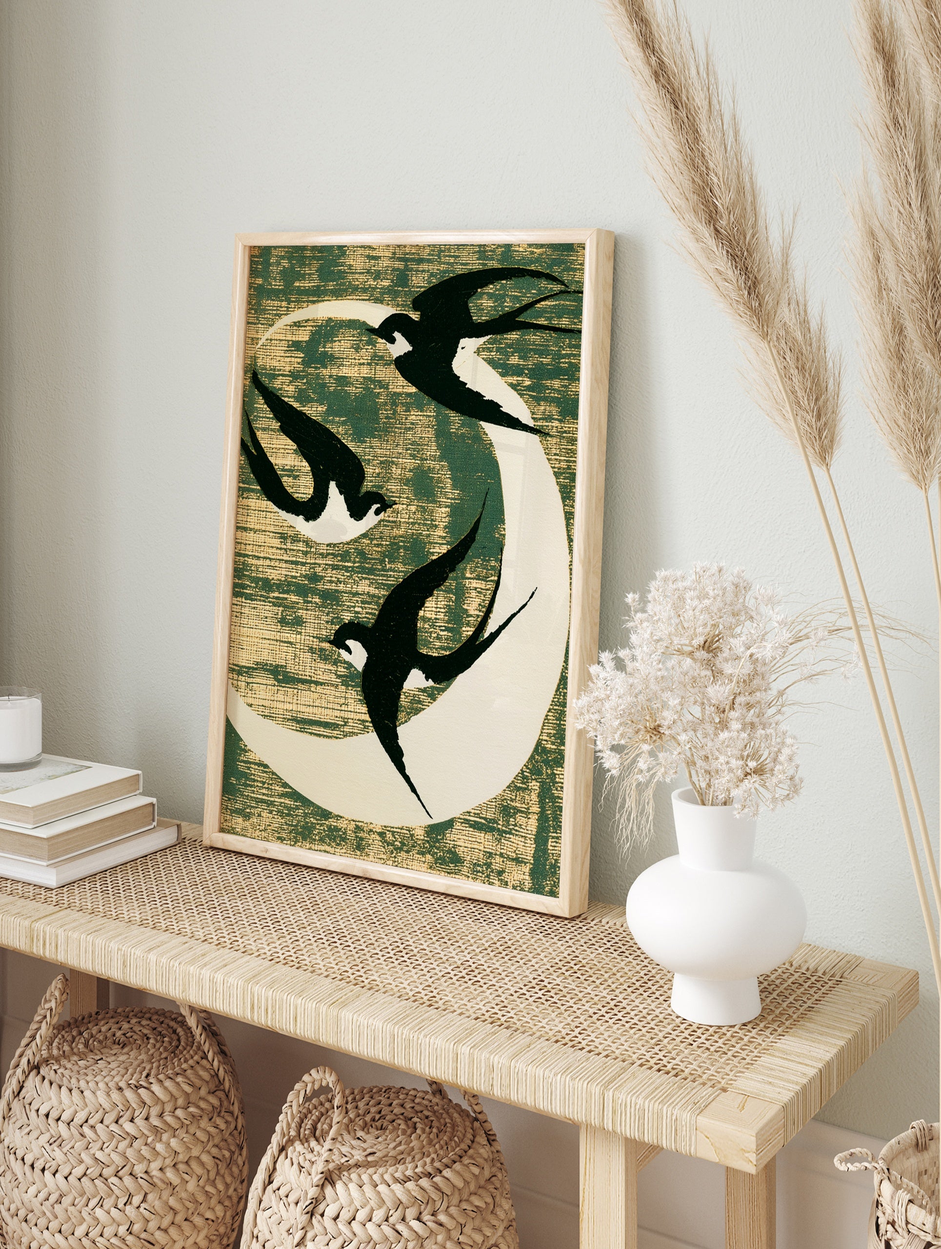 Three black swallows flying against a white moon on a textured dark green background, in an alternate framed mockup