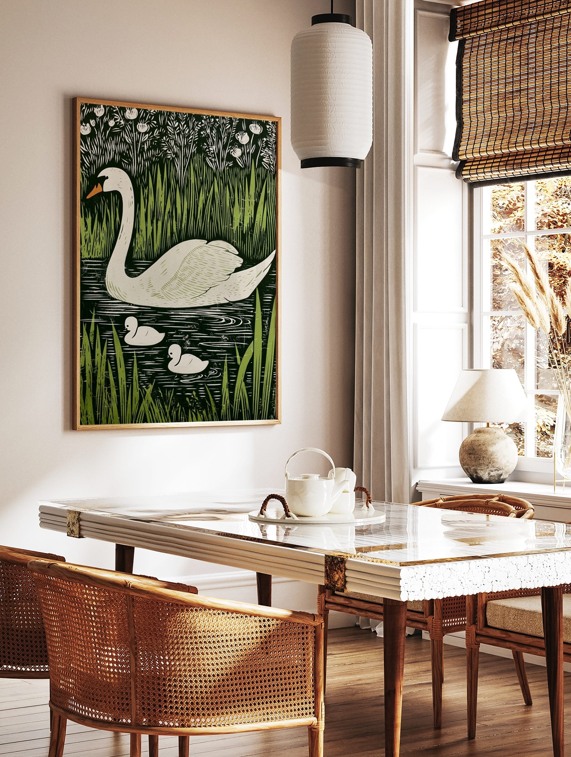 White swan and two cygnets swimming in dark water, surrounded by green reeds and white flowers, in, in a styled room mockup