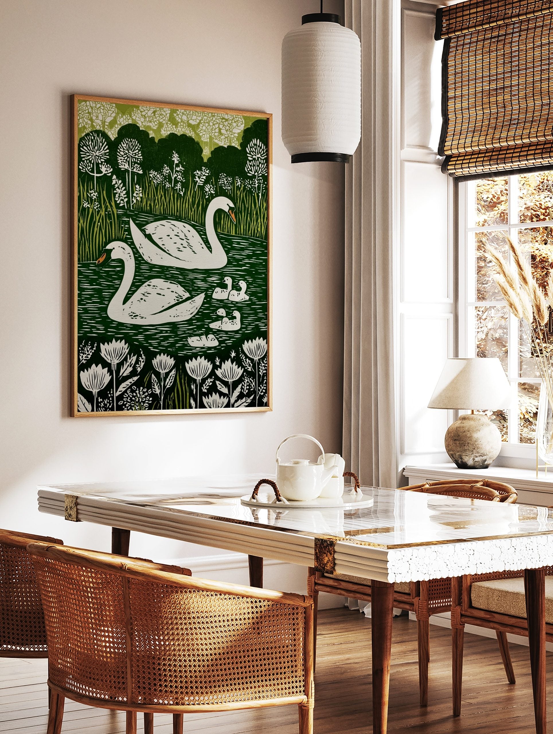 Illustrative print of two white swans and five cygnets on a dark green lake with white flowers and, in a styled room mockup