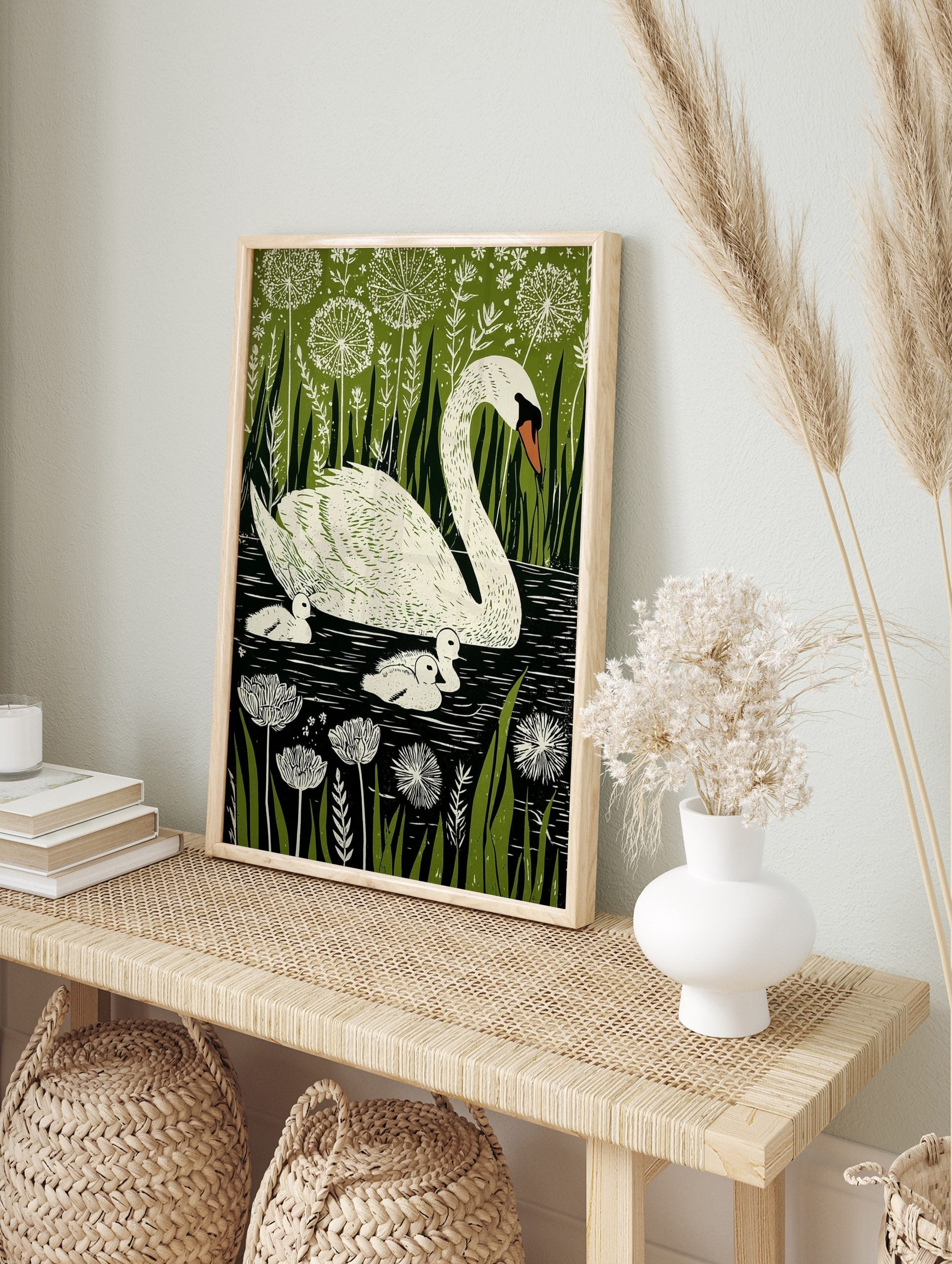 Illustrative print of a white mother swan and three cygnets in dark water, surrounded by, in an alternate framed mockup