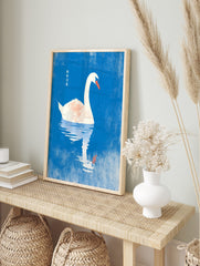 White swan with orange beak floating on blue water with reflection and Chinese text, in an alternate framed mockup