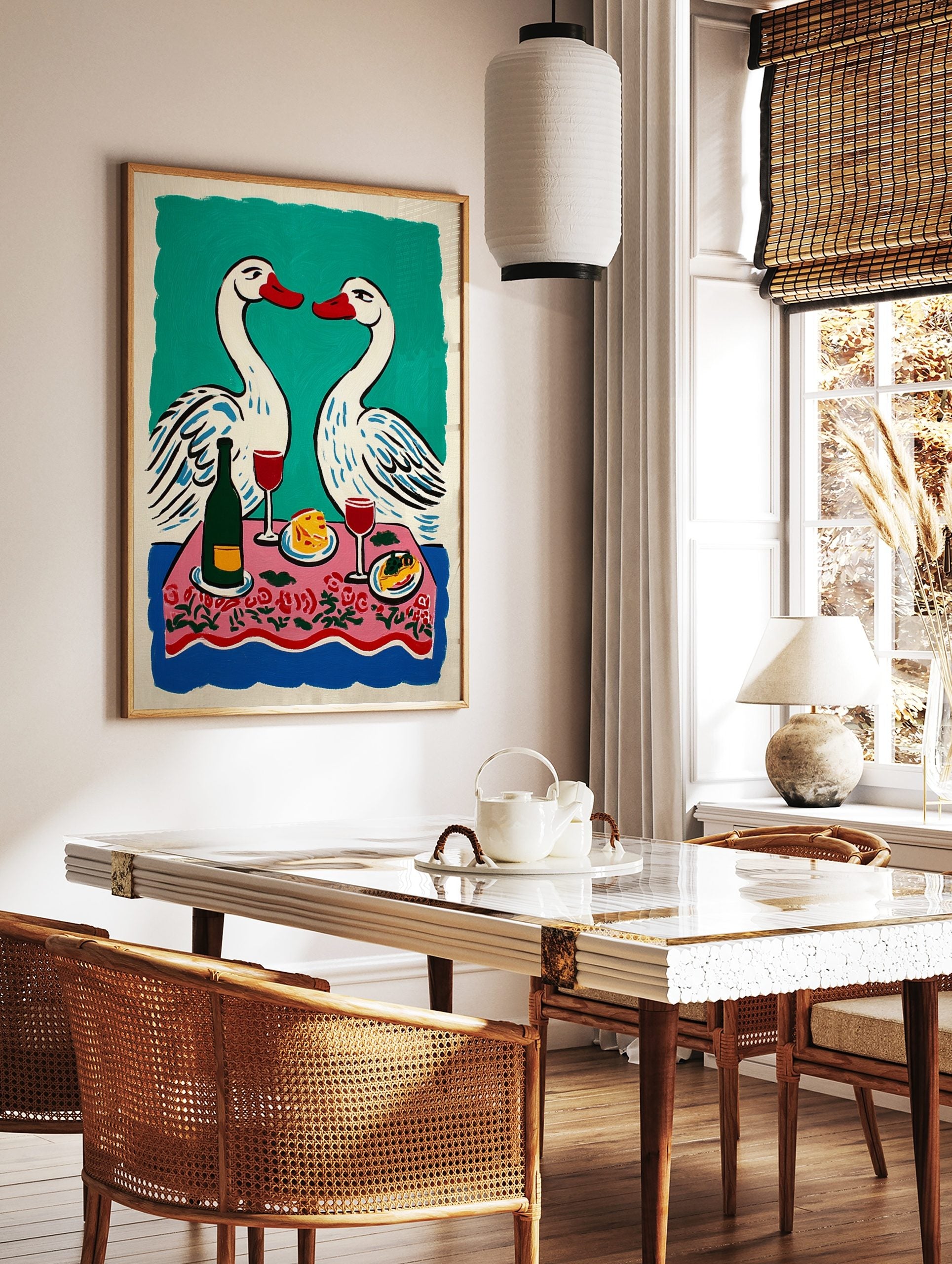 Illustrative print of two white swans with red beaks over a pink floral dinner table with wine and, in a styled room mockup