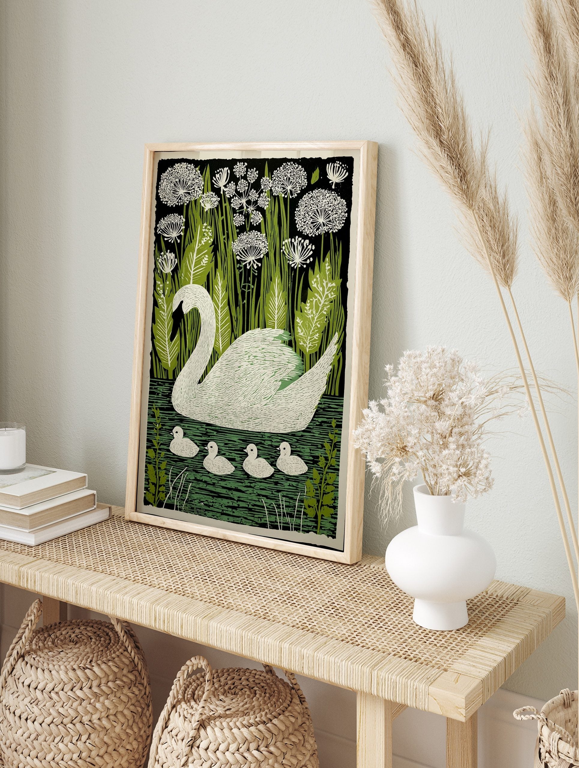 White swan with four cygnets swimming on green water, surrounded by green reeds and white, in an alternate framed mockup