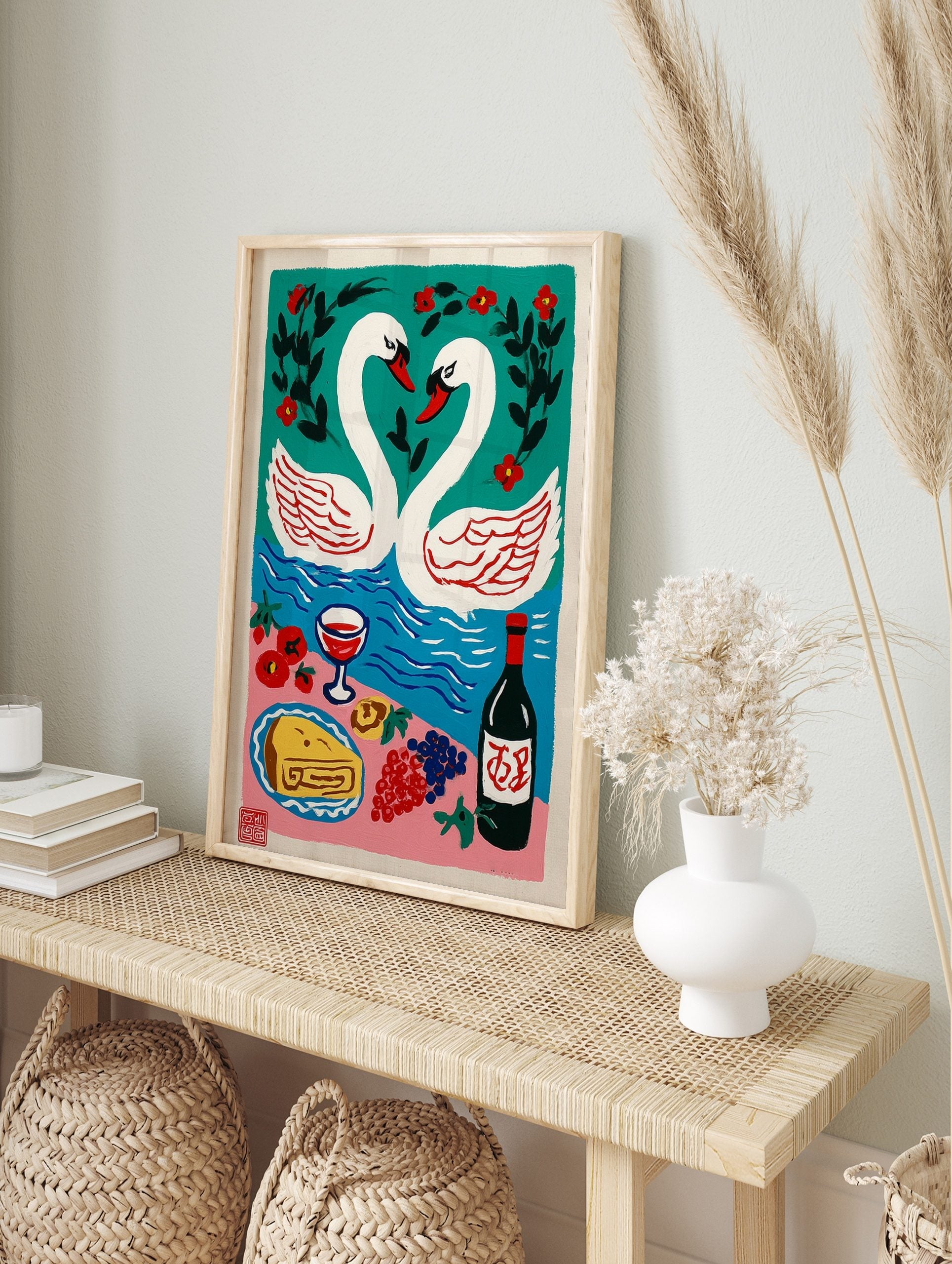 Illustrative art print of two white swans forming a heart, a blue lake, red flowers, and a, in an alternate framed mockup