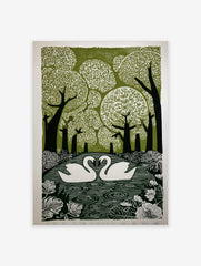 Linocut print of two white swans on water, surrounded by green trees and botanical leaves, forming a heart shape