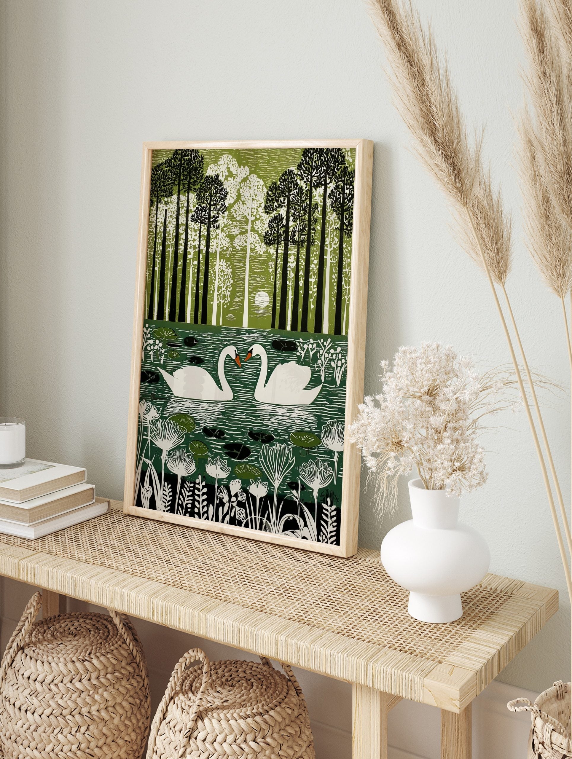 Illustrative green wall art print of two white swans on a pond surrounded by tall trees and, in an alternate framed mockup